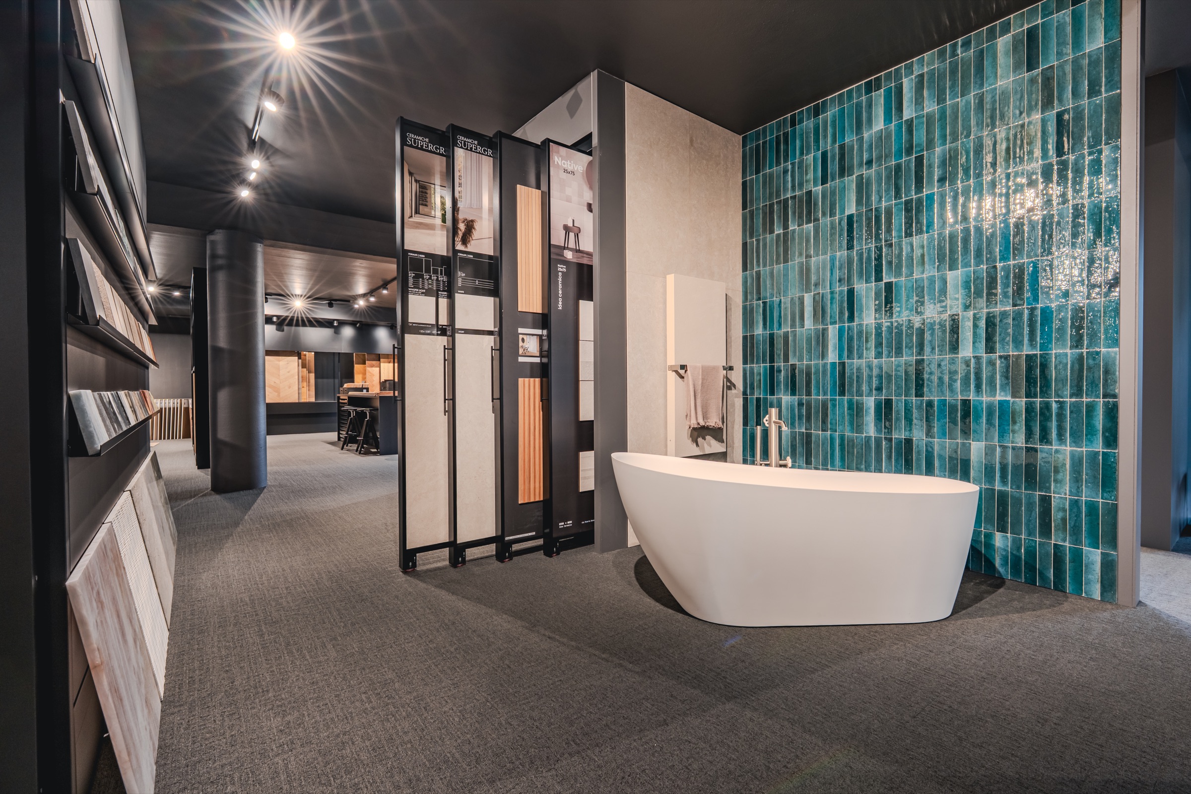 Bagno espositivo con vasca freestanding e parete in ceramica turchese